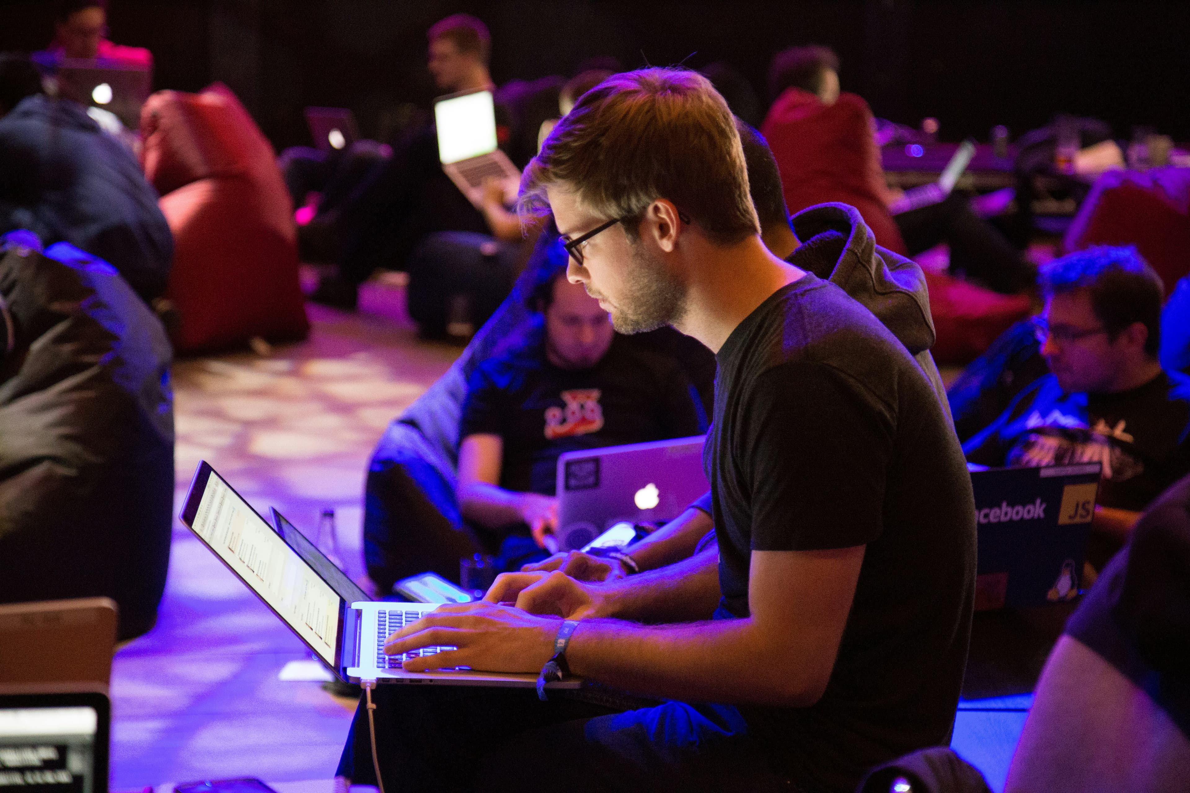 A man sitting with his laptop on his lap at a developers conference