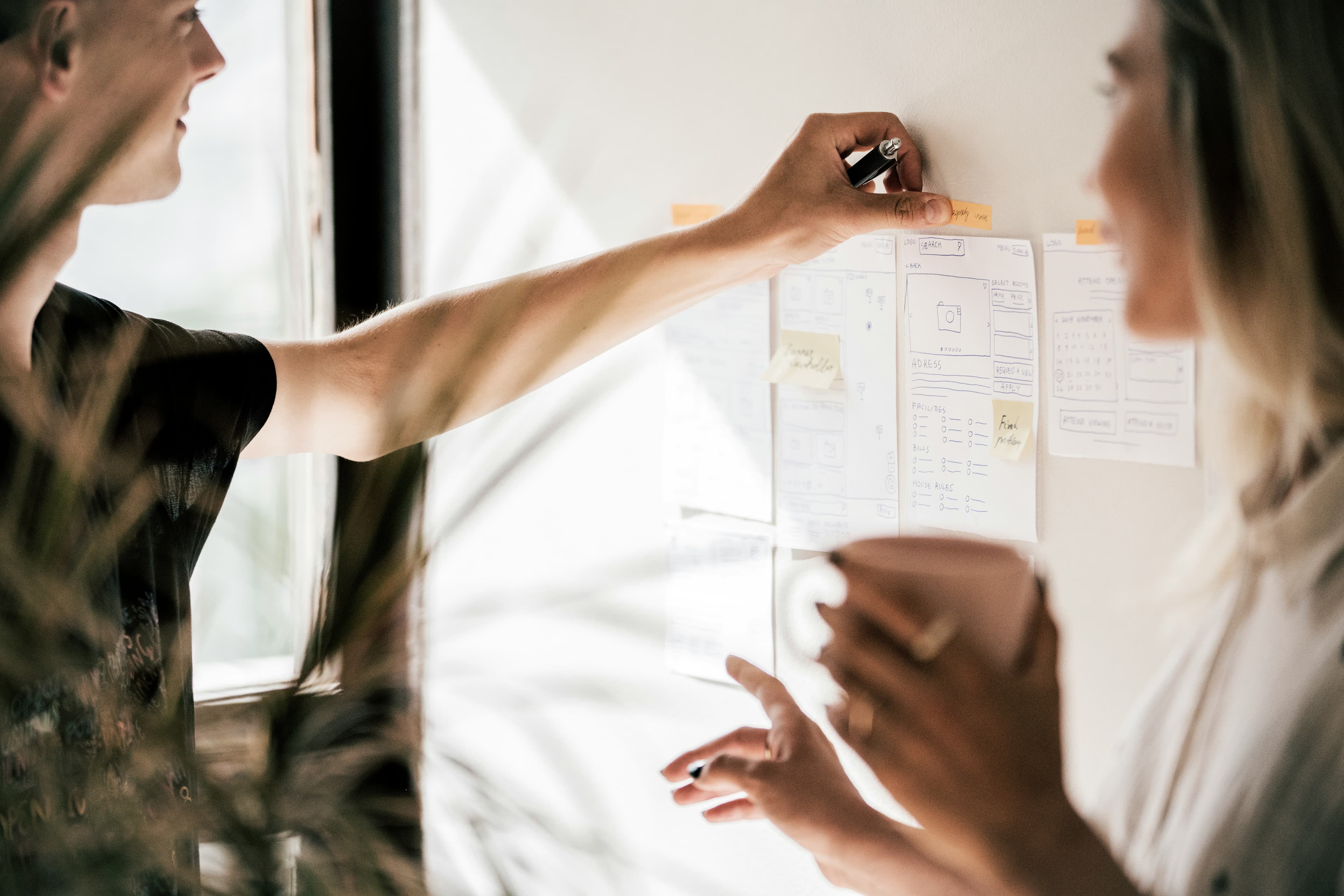 Two people collaborating at work with paper and sticky notes
